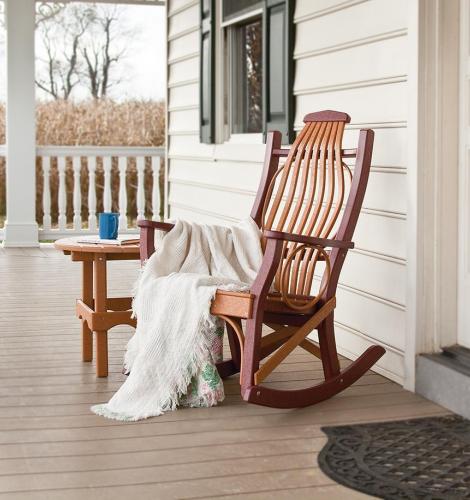 Brown poly rocking chair sits on front porch with white blanket draped over the side and a poly side table to the left.
