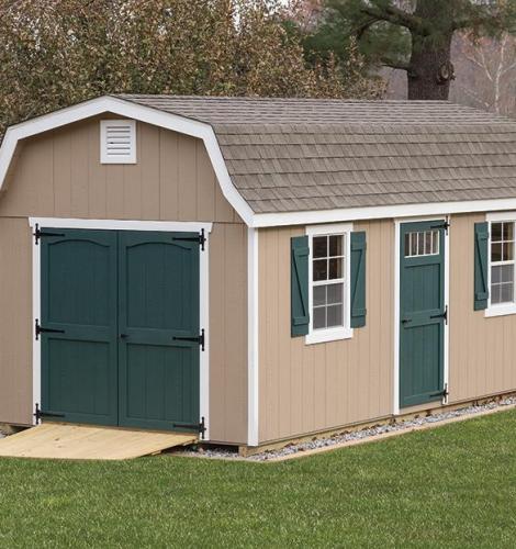 Classic Garden Dutch Barn with tan siding, white trim, dark green doors and shutters, and a brown shingle roof.