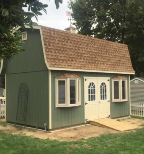 elite classic garden dutch barn with green siding, bay windows, and cream double doors with a ramp