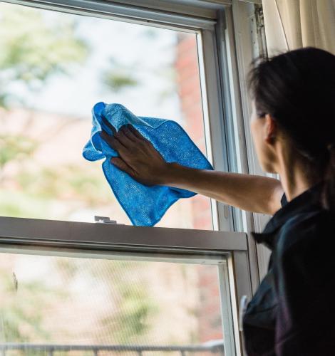 Person cleaning window with a blue rag.