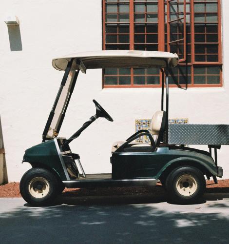 green golf cart against a white wall 