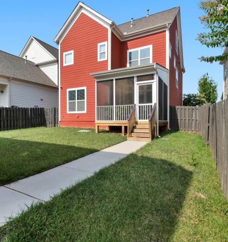 Back view of a 2-story house with a small, fenced-in backyard.