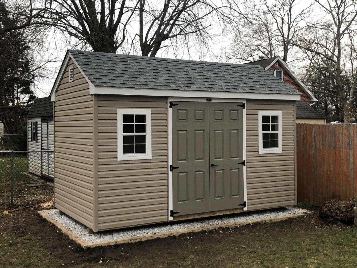 7 foot Cottage Shed with tan vinyl siding, olive green double doors, gray shingle roofing, and white trim.