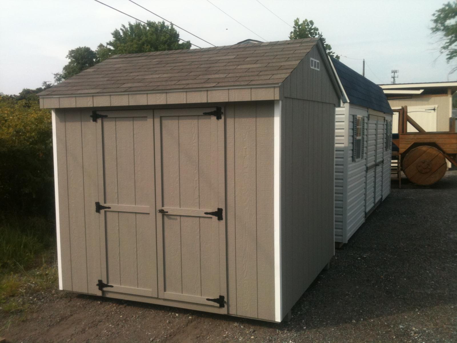 Economy Cottage Shed with tan wood siding, brown asphalt roofing, and white trim.
