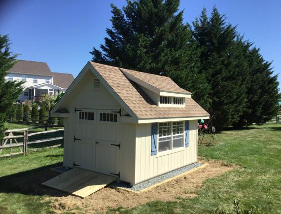 deluxe classic cottage shed with cream siding, blue shutters, double door, ramp, and dormer