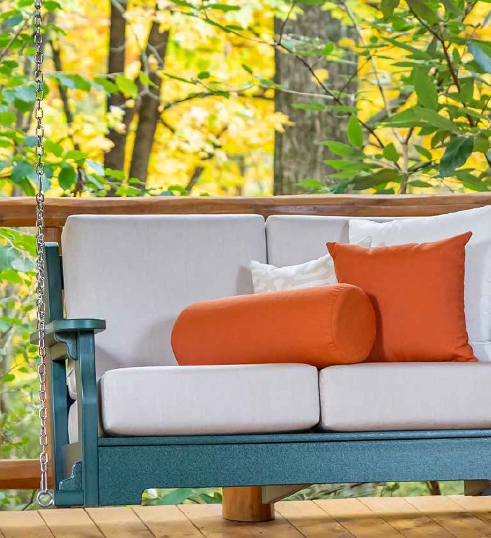 Teal poly wood porch swing with white cushions and orange throw pillows.
