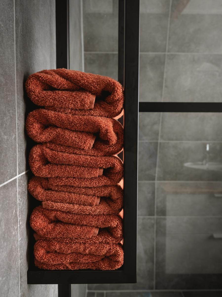 Orange towels stacked vertically in a wall rack.